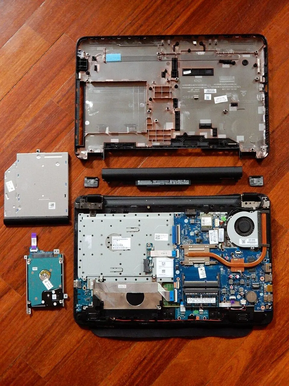 Disassembled laptop showing the logic board, battery, storage drive, and cooling fan
